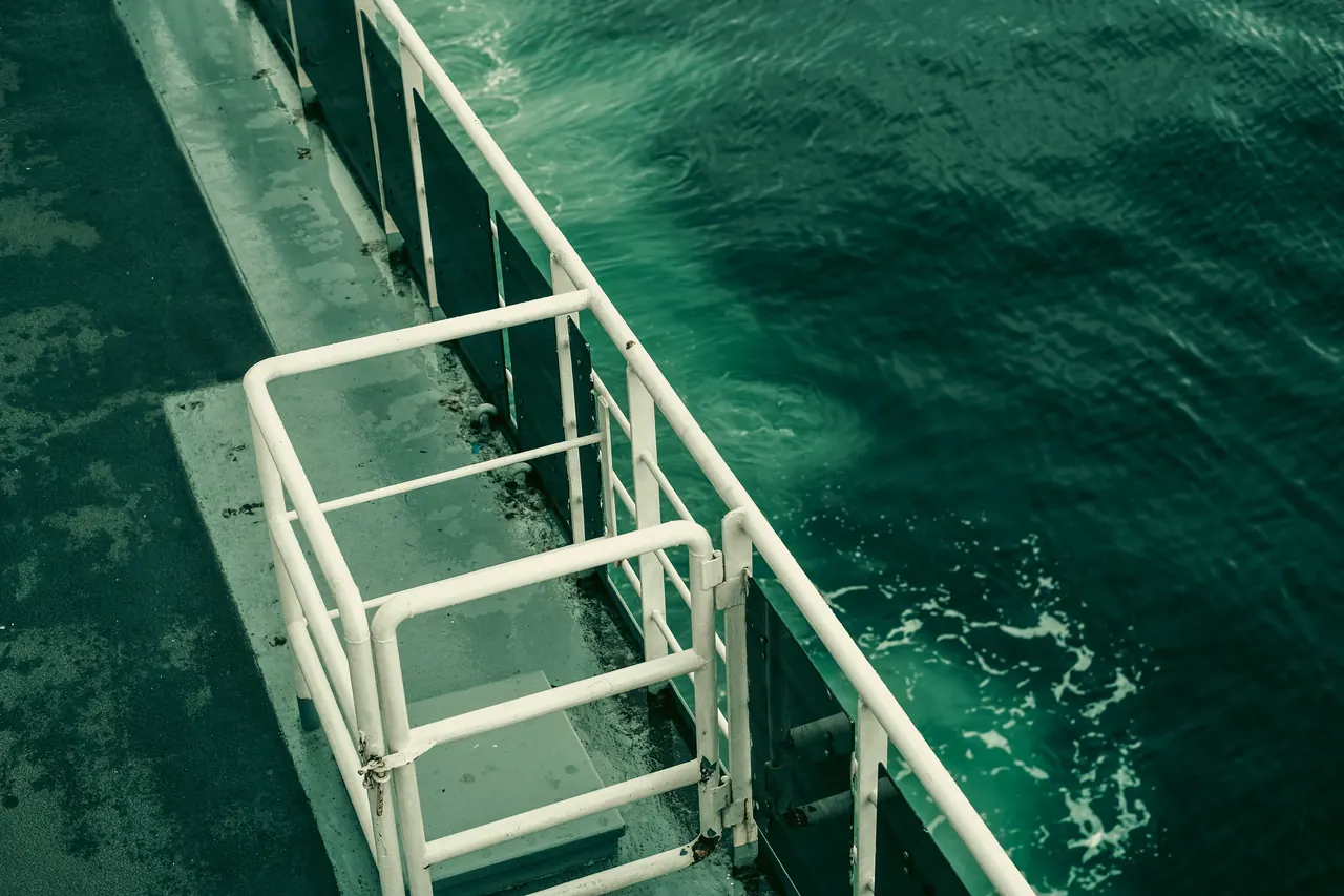 A ship’s deck with railing over green ocean water, capturing tranquility and travel mood.