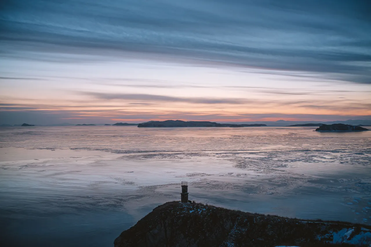 Peaceful coastal scene showcasing a serene ocean and islands at sunset.