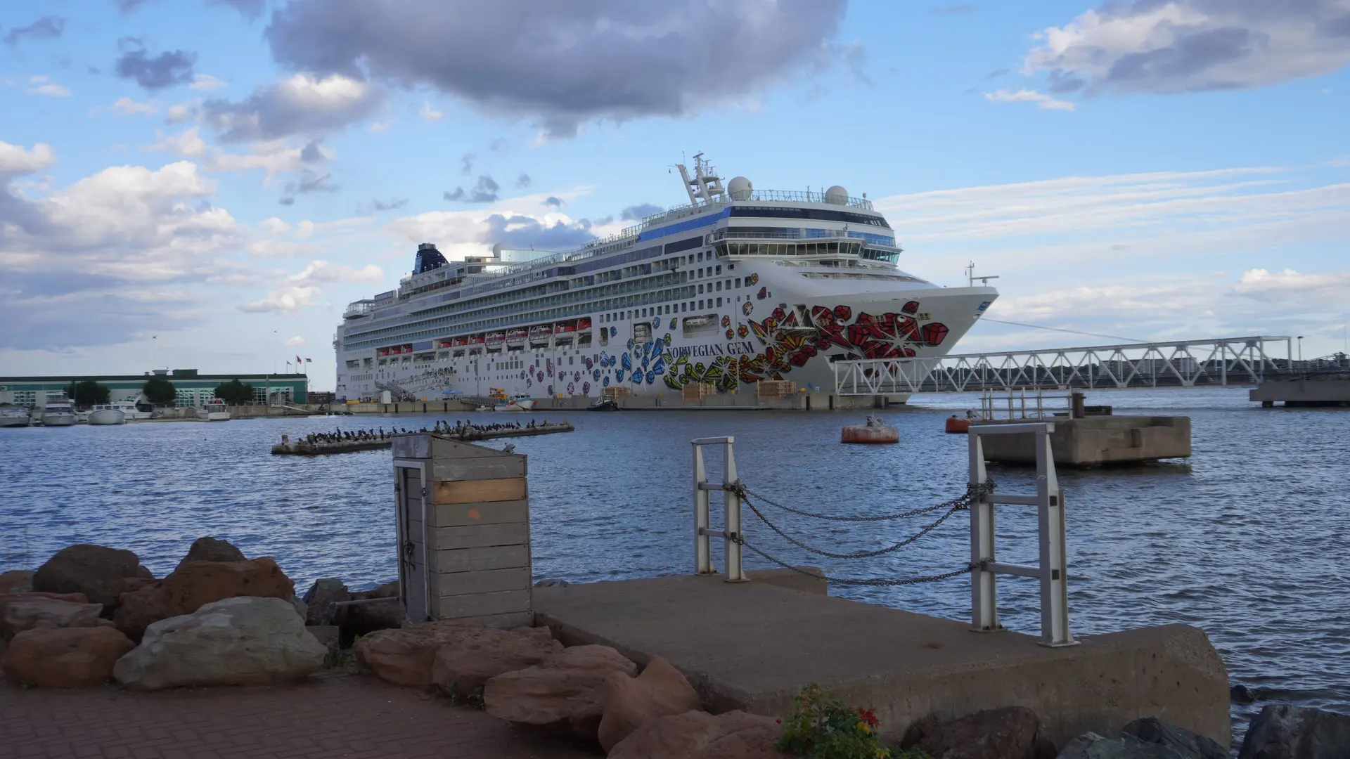 A large cruise ship berthed alongside a pier under a bright sky