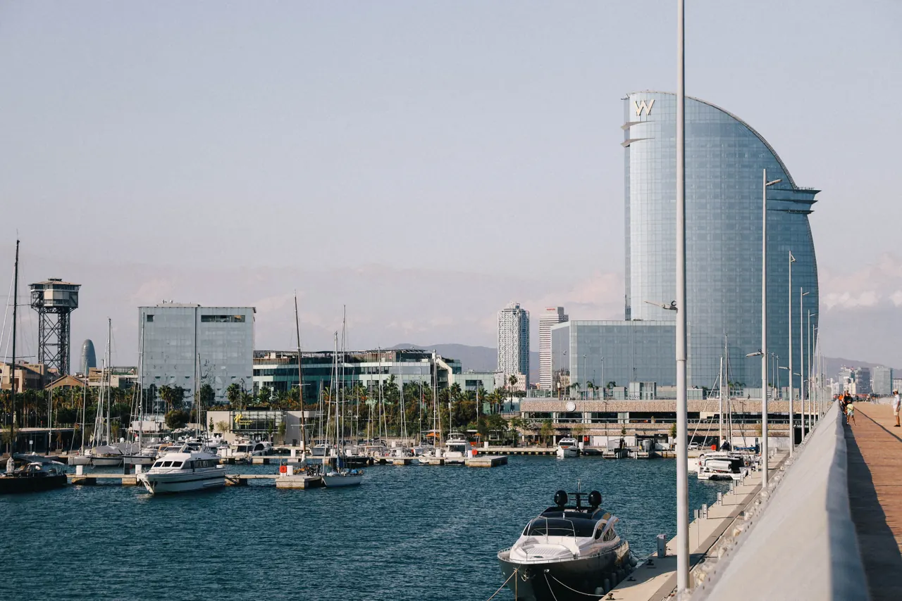 Modern architecture and boats in Barcelona’s scenic harbor, with iconic skyline views.