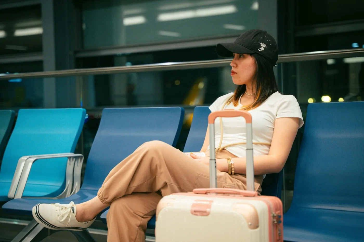 A traveler waiting with luggage in an airport terminal, checking a phone