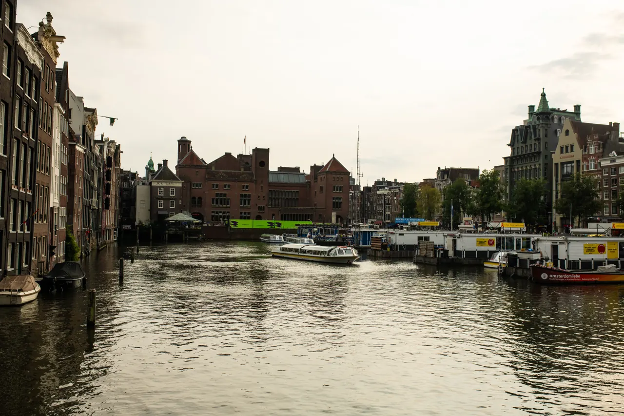A picturesque view of Amsterdam canals with historic buildings and boats on a cloudy day.