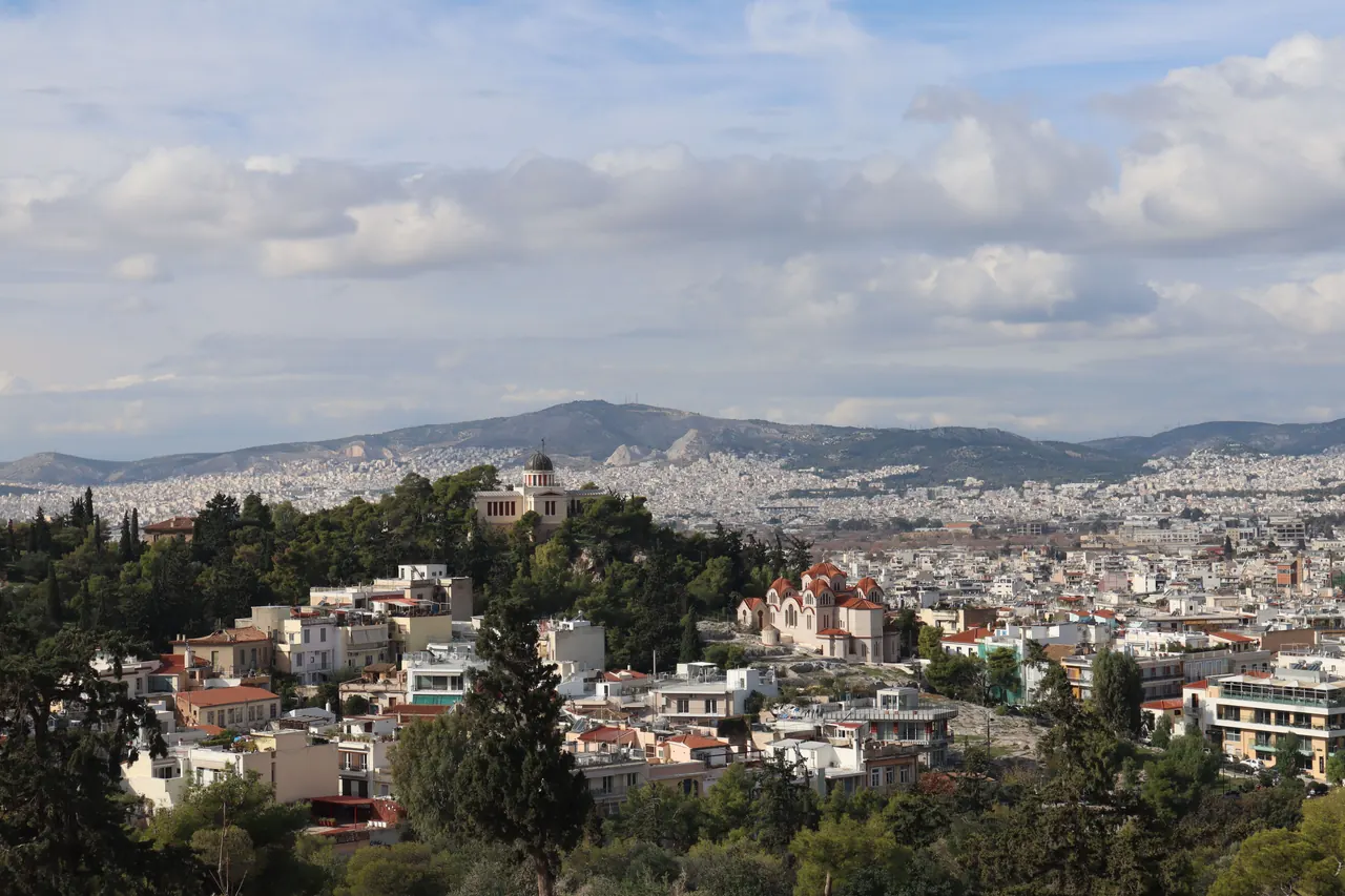 Overlooking Athens skyline with mountains and sea, showcasing vibrant urban architecture and coastal beauty.