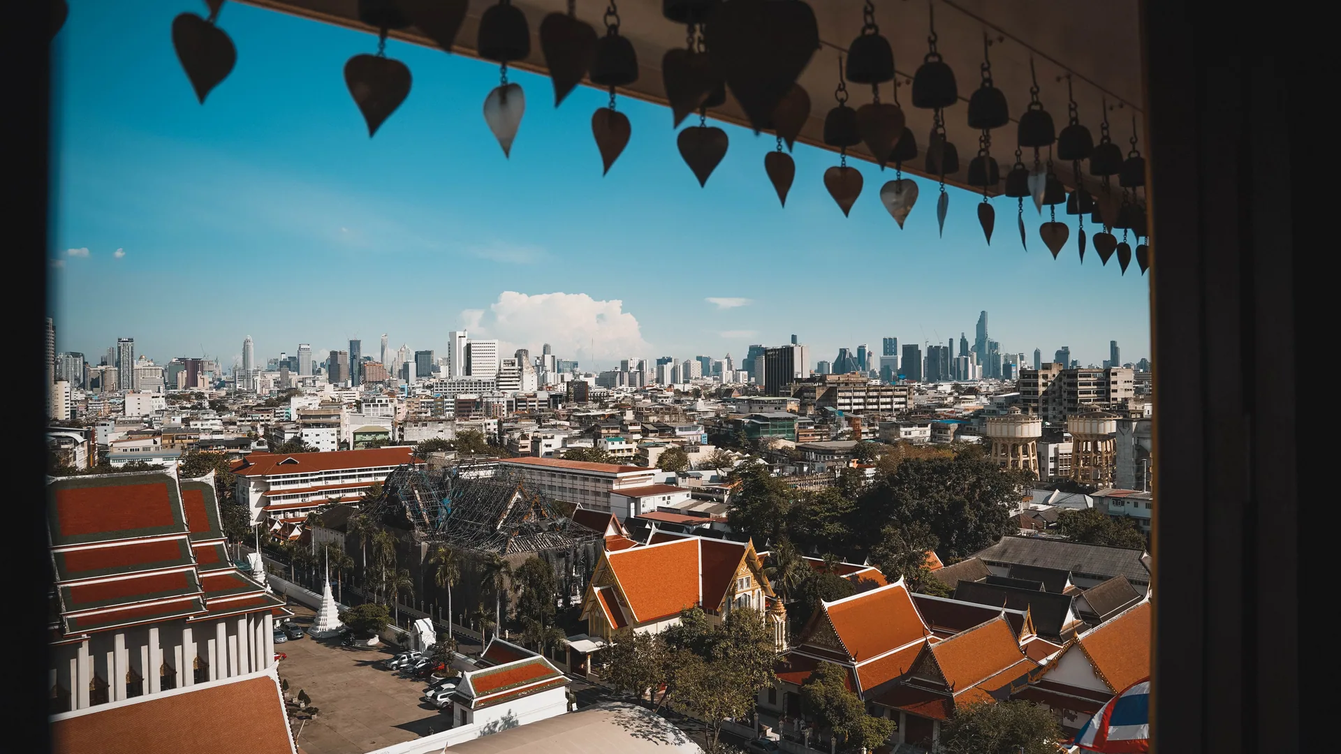Bangkok’s high-rise skyline rising behind the tiered roofs of a traditional Thai temple