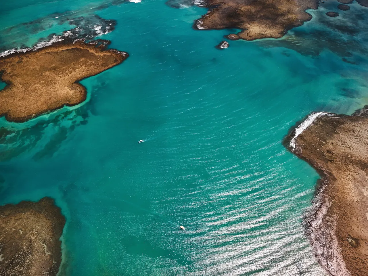 Stunning aerial photo of turquoise coastal waters with small islands and boats, showing natural beauty.