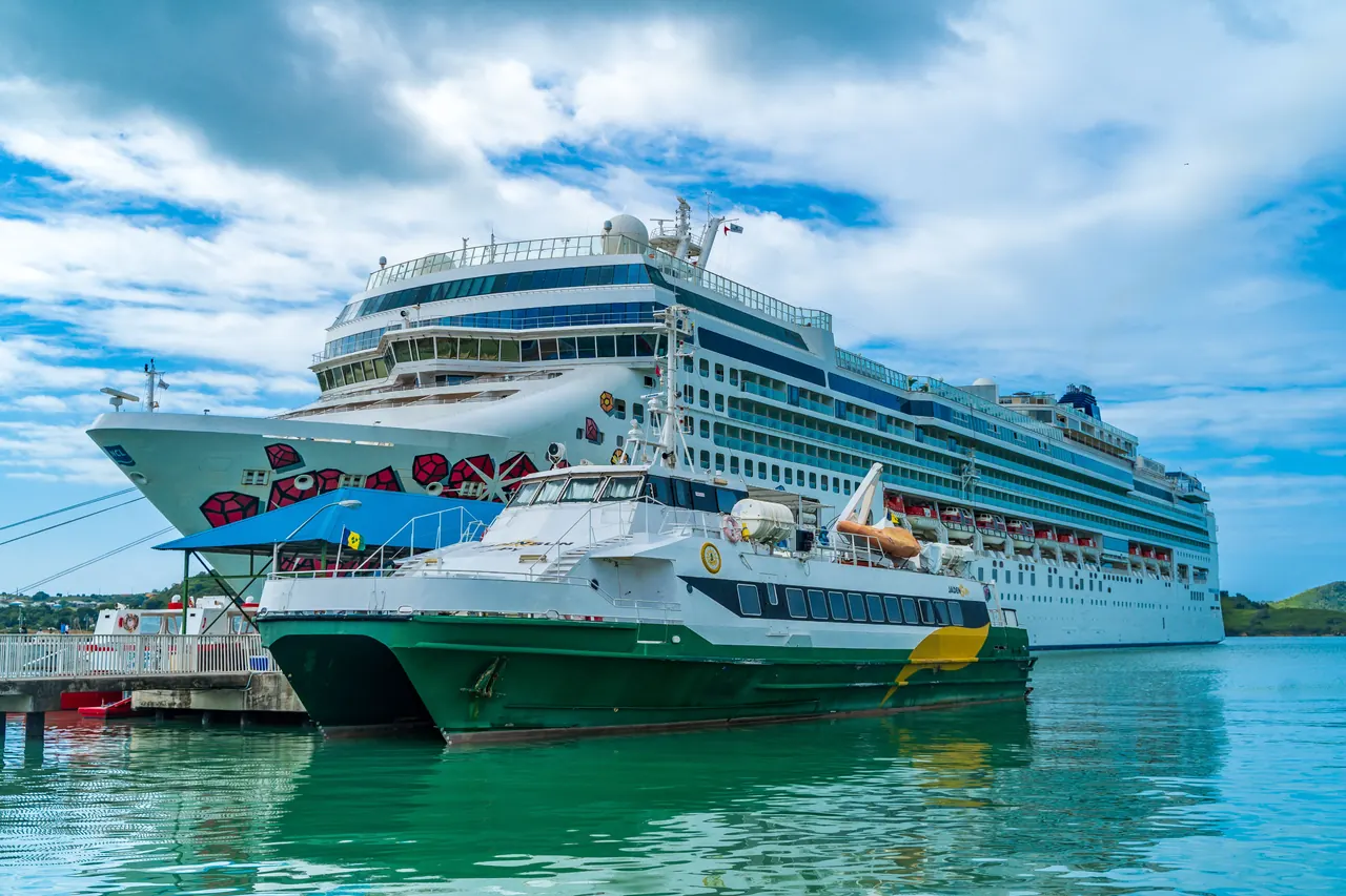 Scenic view of a cruise ship and ferry docked in Antigua’s turquoise waters under a blue sky.