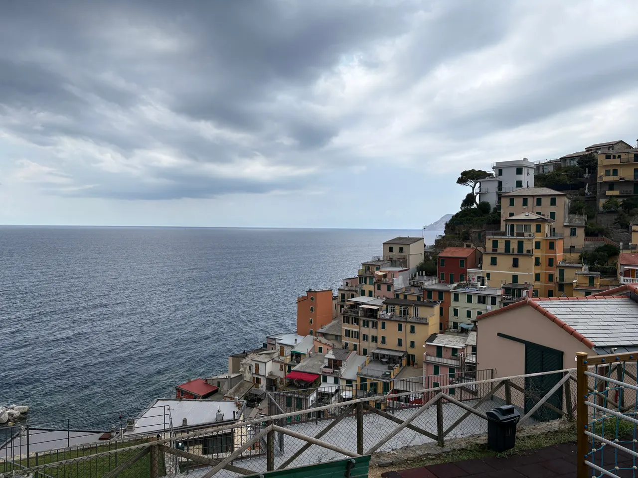 Vibrant coastal view of Riomaggiore, a picturesque village in Liguria, Italy, under overcast skies.