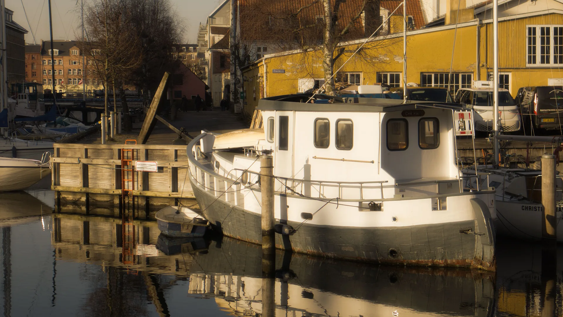 A Copenhagen canal at sunset with boats reflected in still water