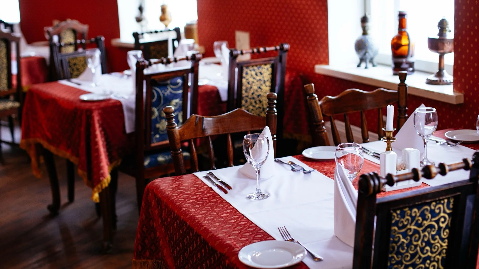 A formally laid dining room with glassware, cutlery and folded napkins across long tables