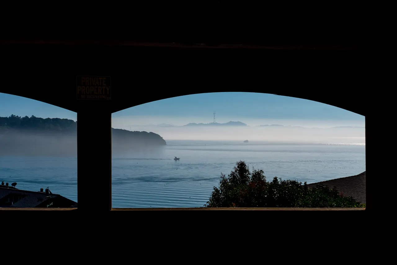Tranquil ocean view framed by window, capturing misty morning over scenic coastline.