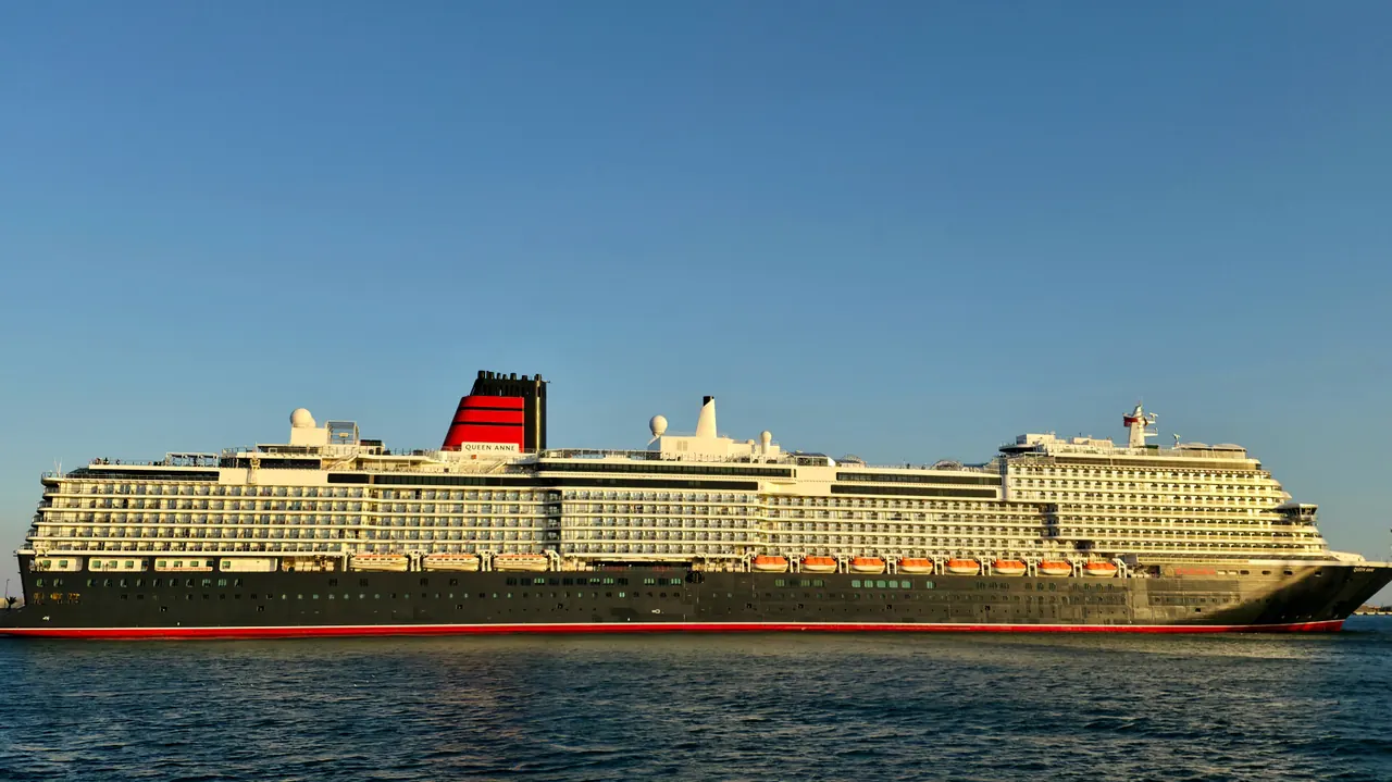 A majestic luxury cruise ship sailing in calm seas under a clear blue sky.