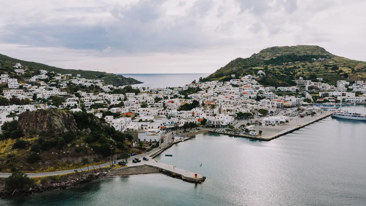 Aerial view of the picturesque Patmos harbor with traditional whitewashed buildings and lush hills.