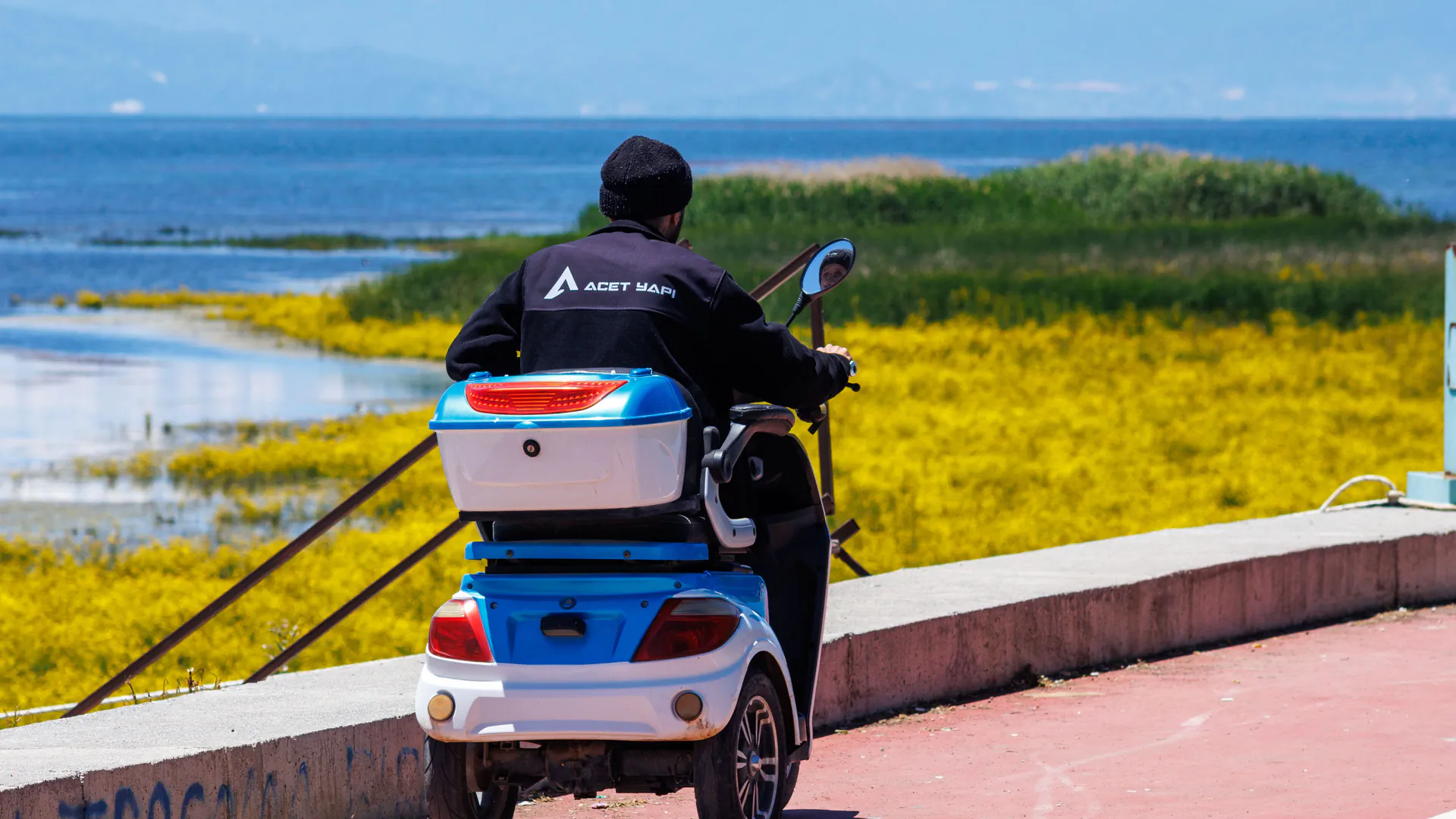 A person riding a mobility scooter along a paved lakeside path