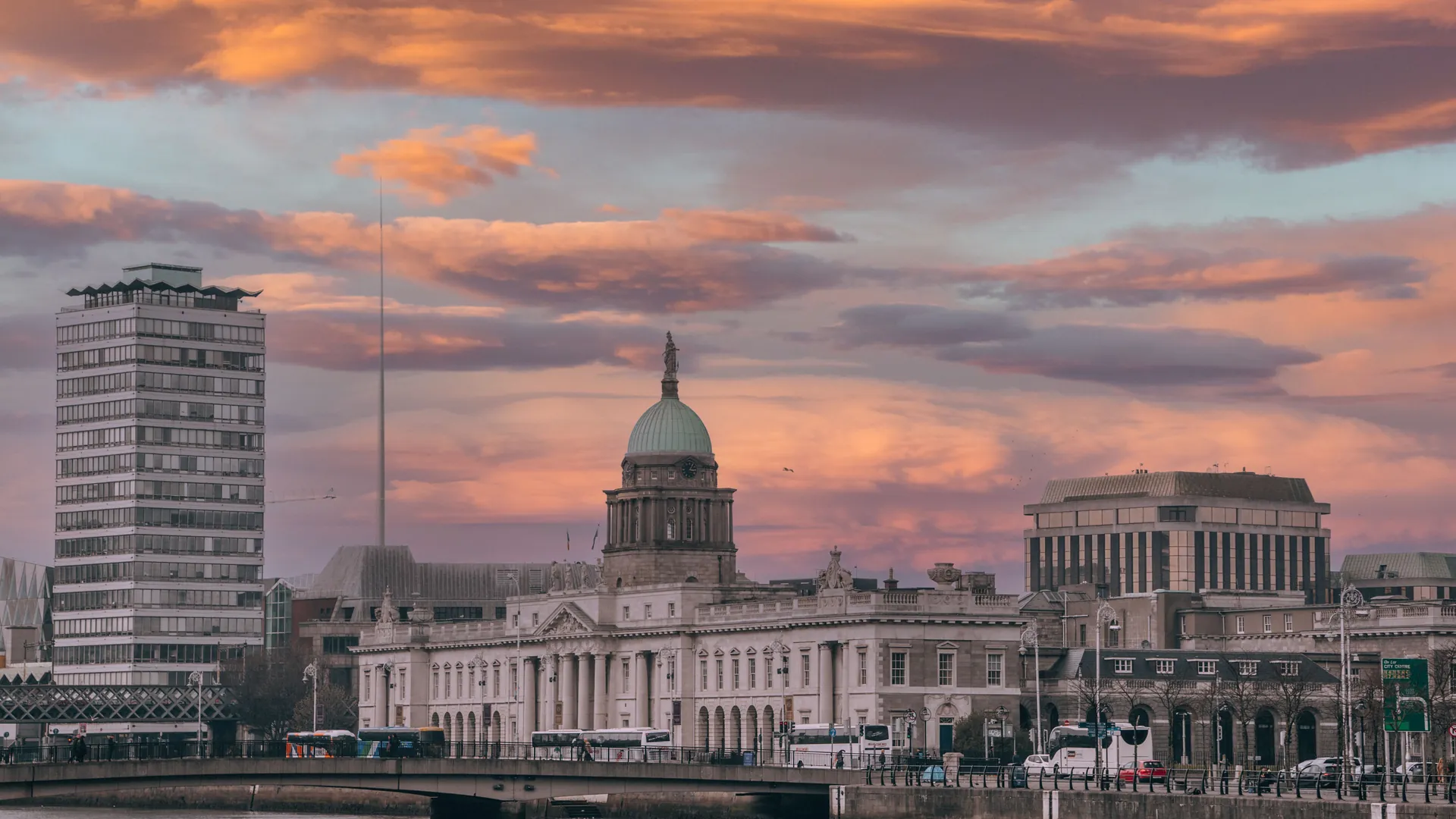 Dublin's Custom House seen across the River Liffey at sunset, its dome and columns lit against a warm sky