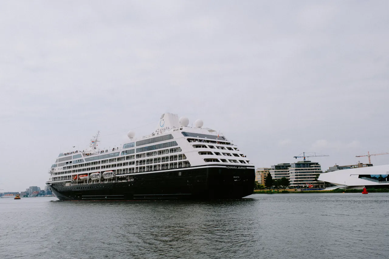 A luxury cruise ship stationed in a city harbor, surrounded by modern architecture.