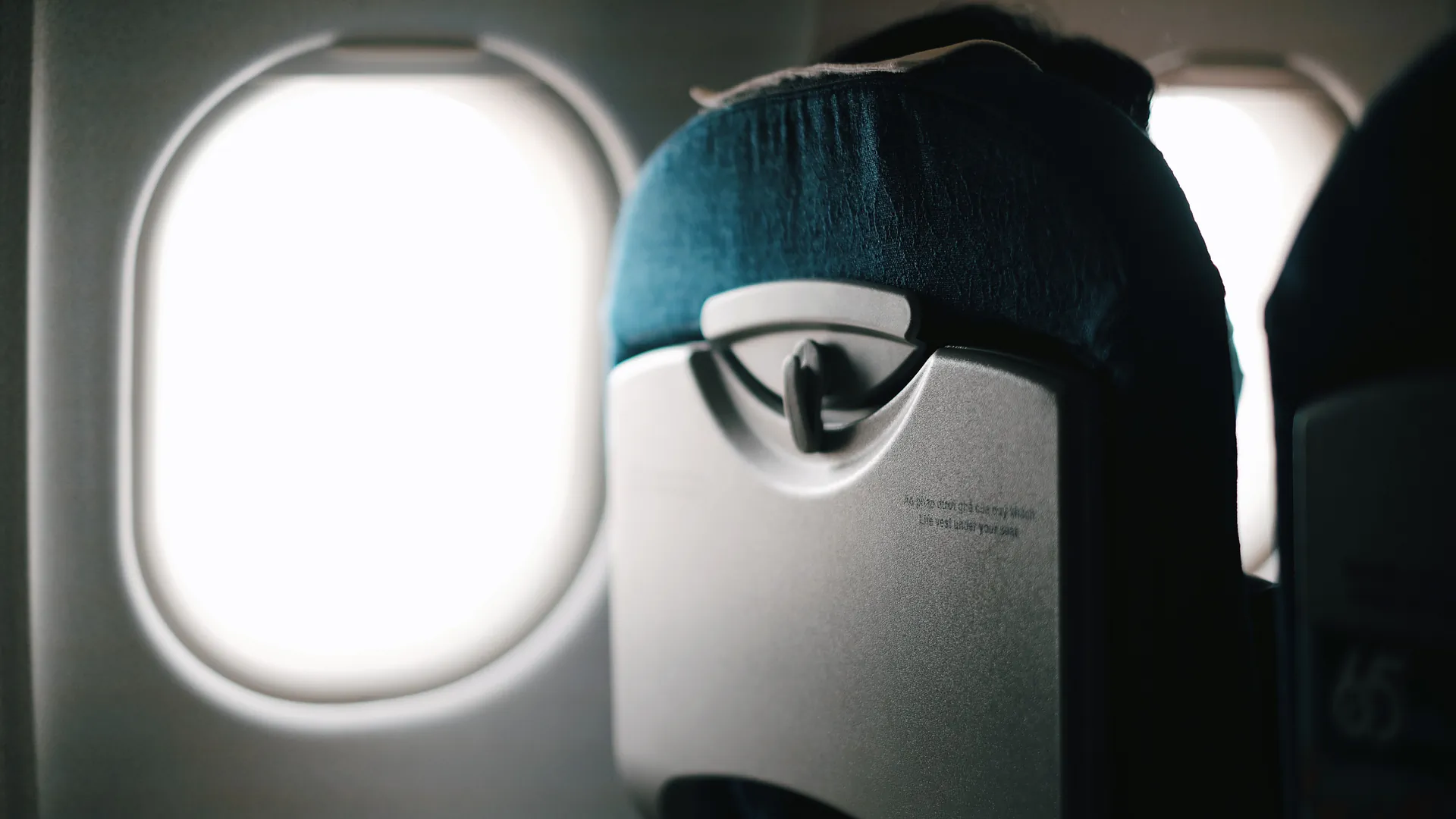 An aircraft window seat with bright sky visible outside