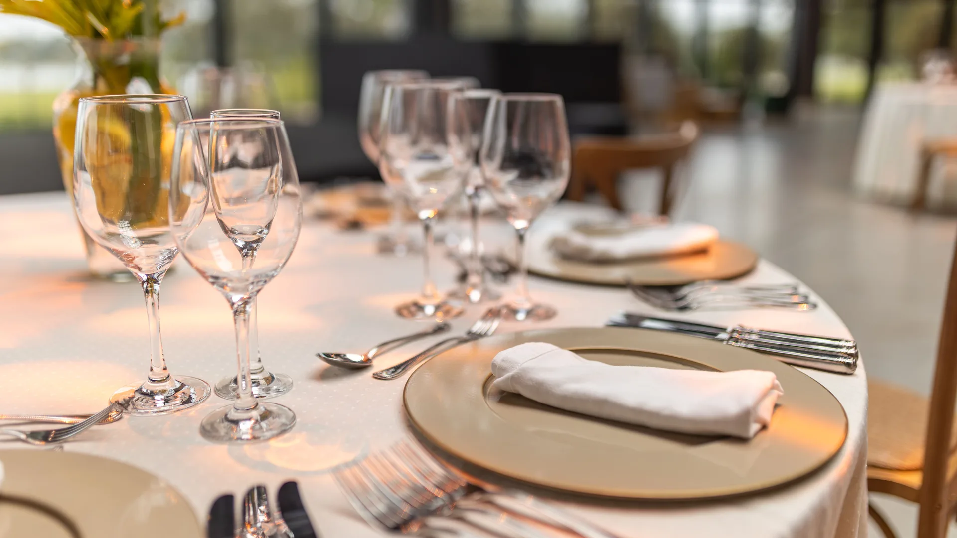 A formally set dining table with glassware and folded napkins