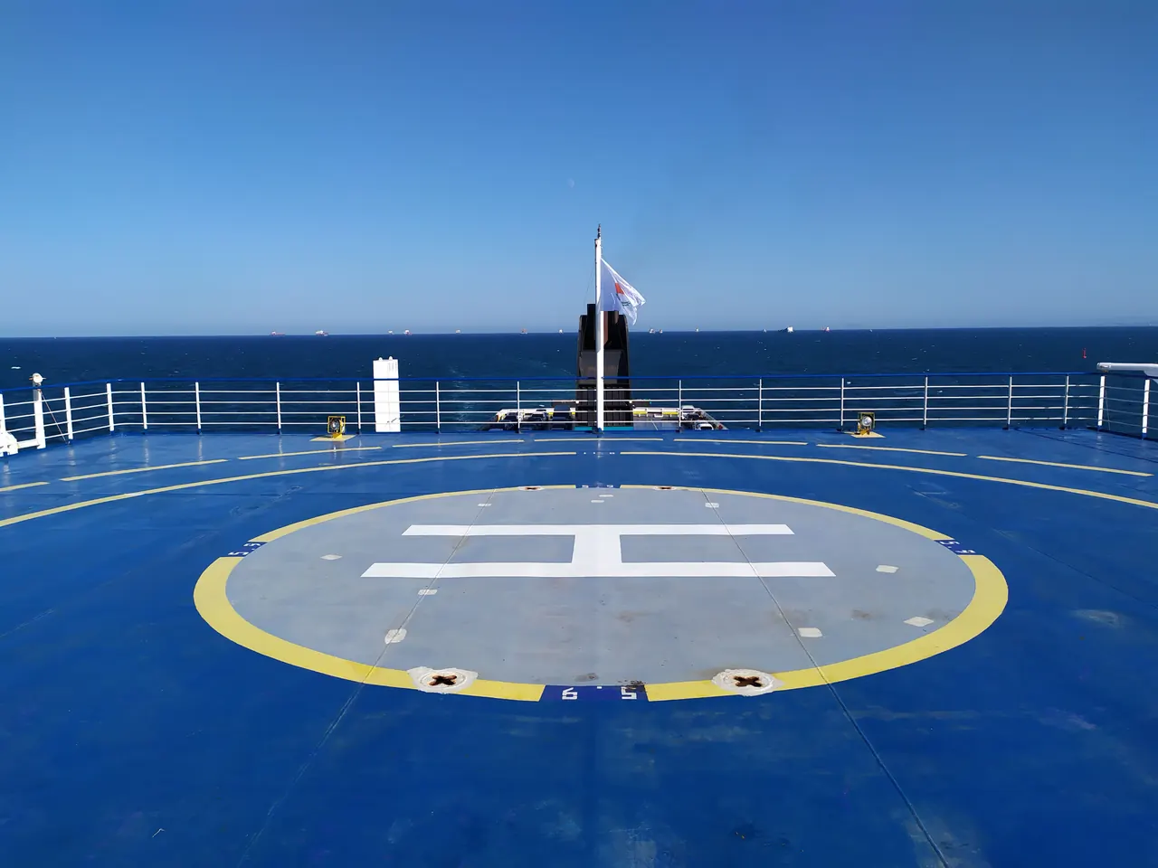 A helipad on a ship deck with a clear blue sea and sky, ideal for travel and maritime themes.
