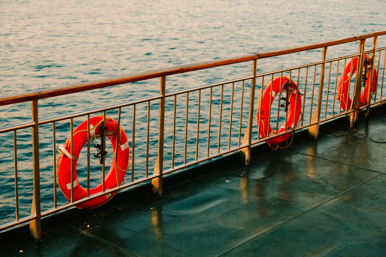 View of ship deck with lifebuoys and calm sea, capturing serene ocean travel.
