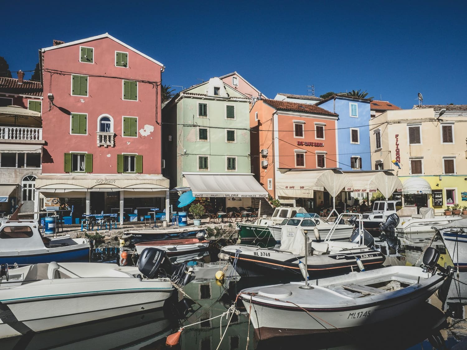 The colour-washed harbour of Veli Lošinj, Croatia — pastel buildings, docked boats and waterfront restaurants