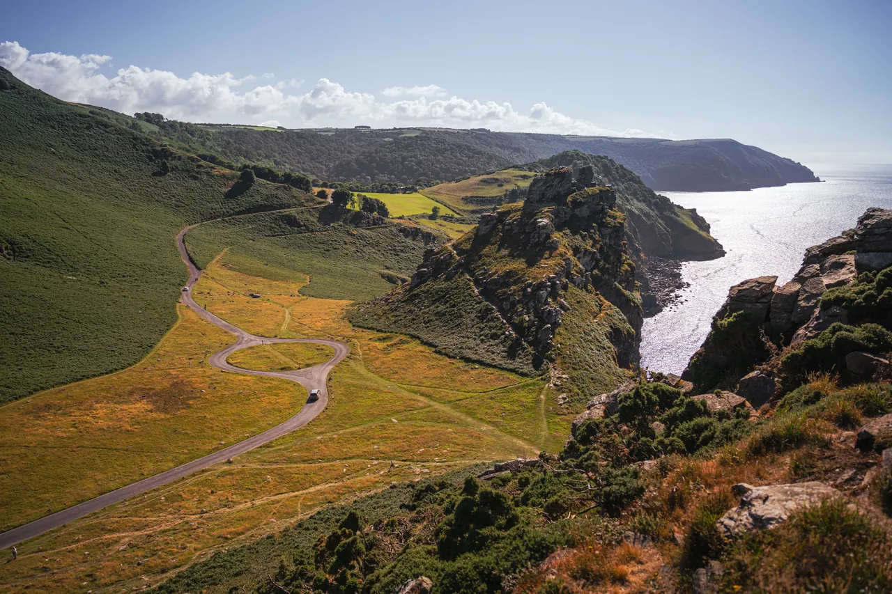 Explore the serene beauty of rolling hills and coastal cliffs under a clear blue sky.