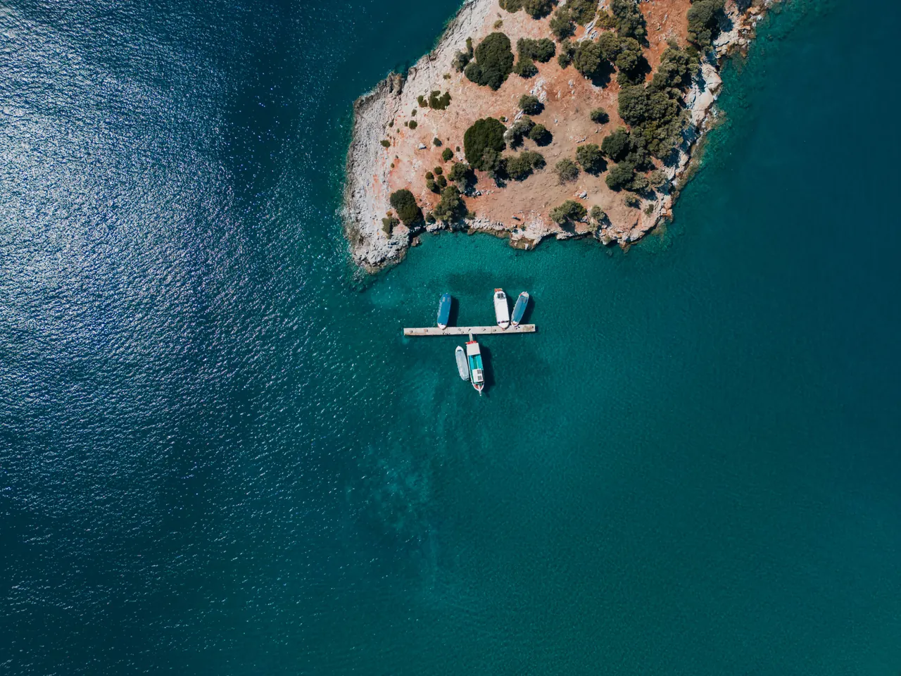 Stunning aerial view of boats moored at a dock in Muğla, Türkiye, with a turquoise sea.