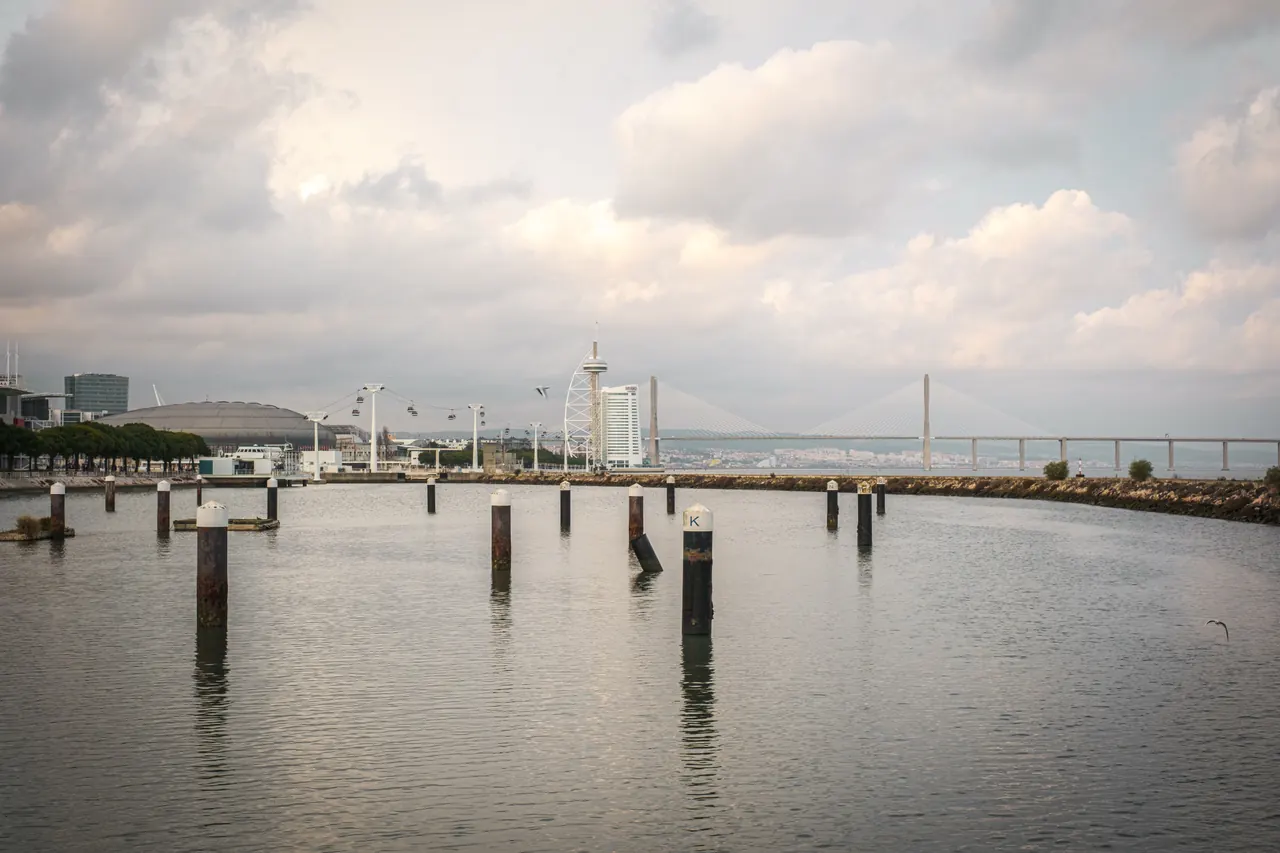 Beautiful view of Lisbon waterfront showcasing the Vasco da Gama Bridge under a cloudy sky.