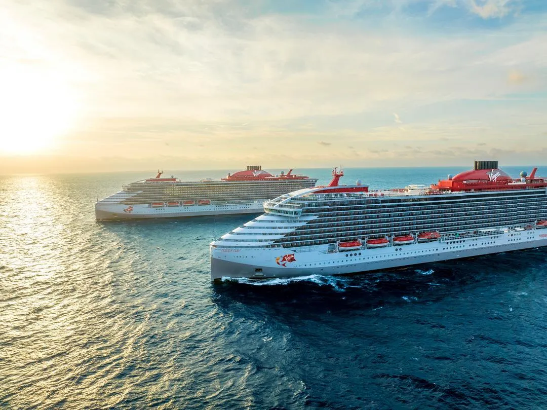 Virgin Voyages Scarlet Lady and Valiant Lady sailing together at sea — MNVV-eligible fleet