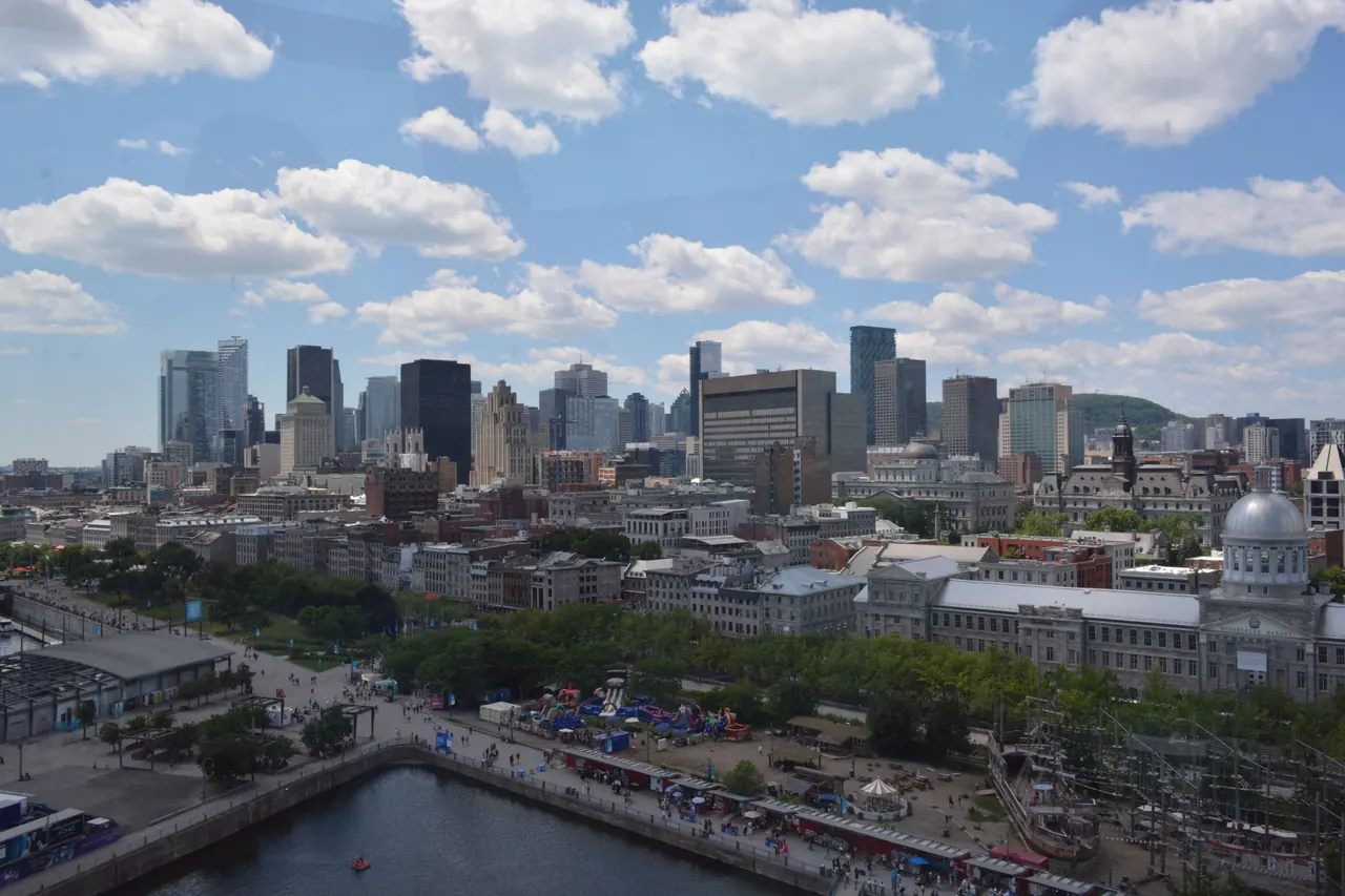 Aerial view of Montreal’s skyline under a bright blue sky with fluffy clouds.