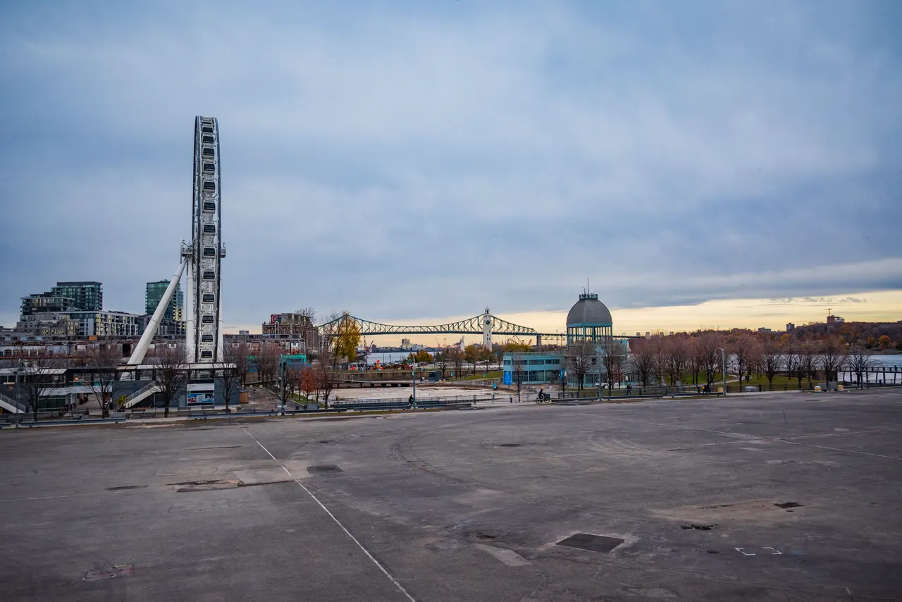 Scenic view of Montréal’s Old Port with a Ferris wheel and urban skyline under a serene sky.