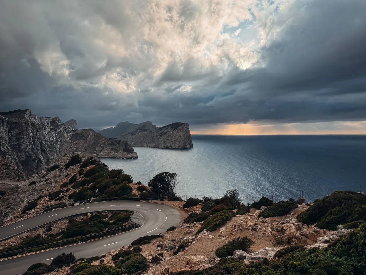 Captivating coastal road view in Mallorca, Spain with dramatic cliffs and sea under a cloudy sky.