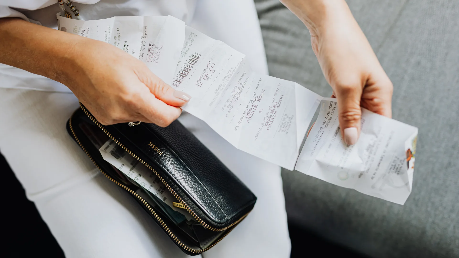 A pair of hands sorting paper receipts taken from a wallet