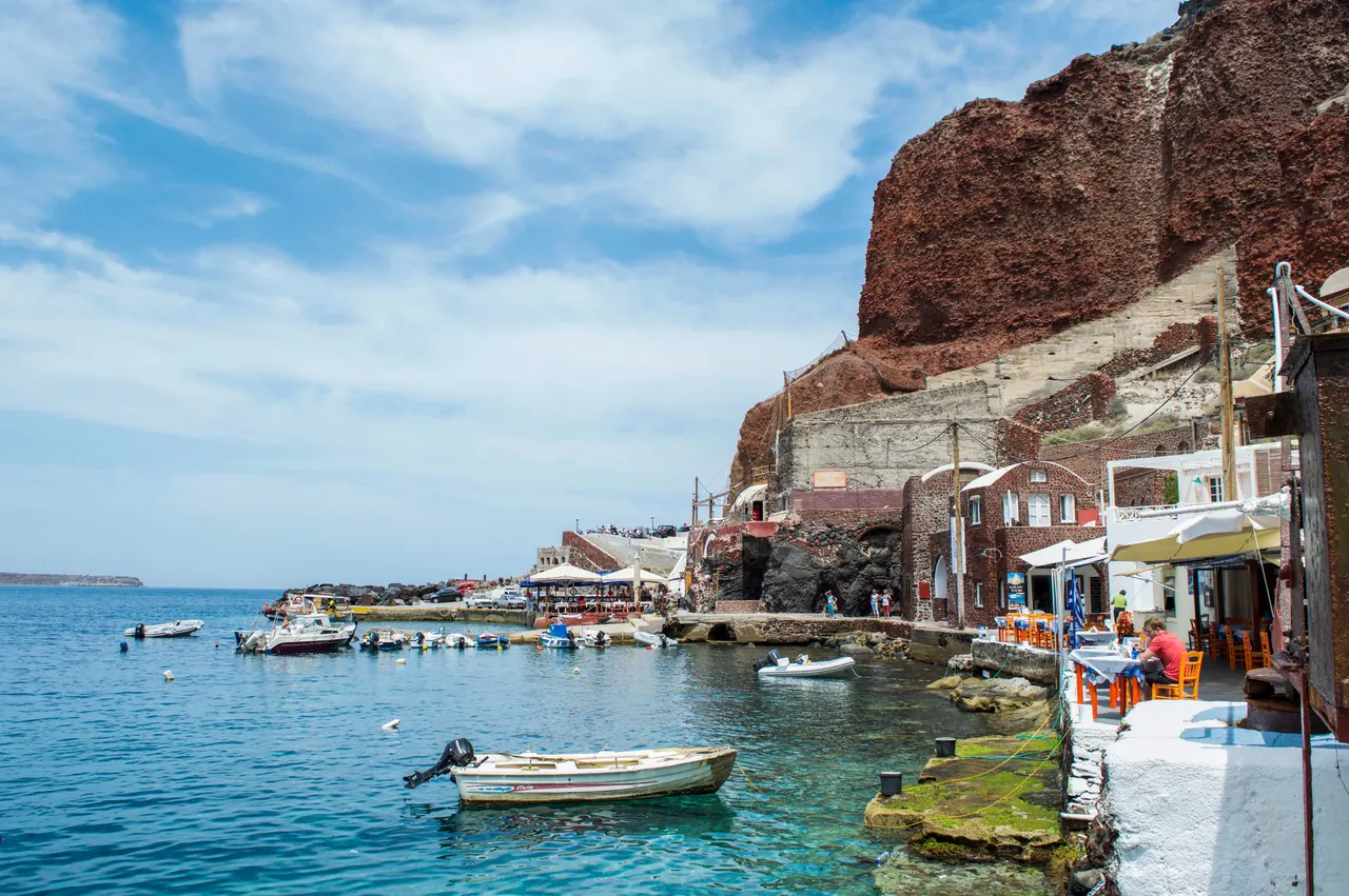 Picturesque view of Santorini’s harbor with boats and iconic architecture.