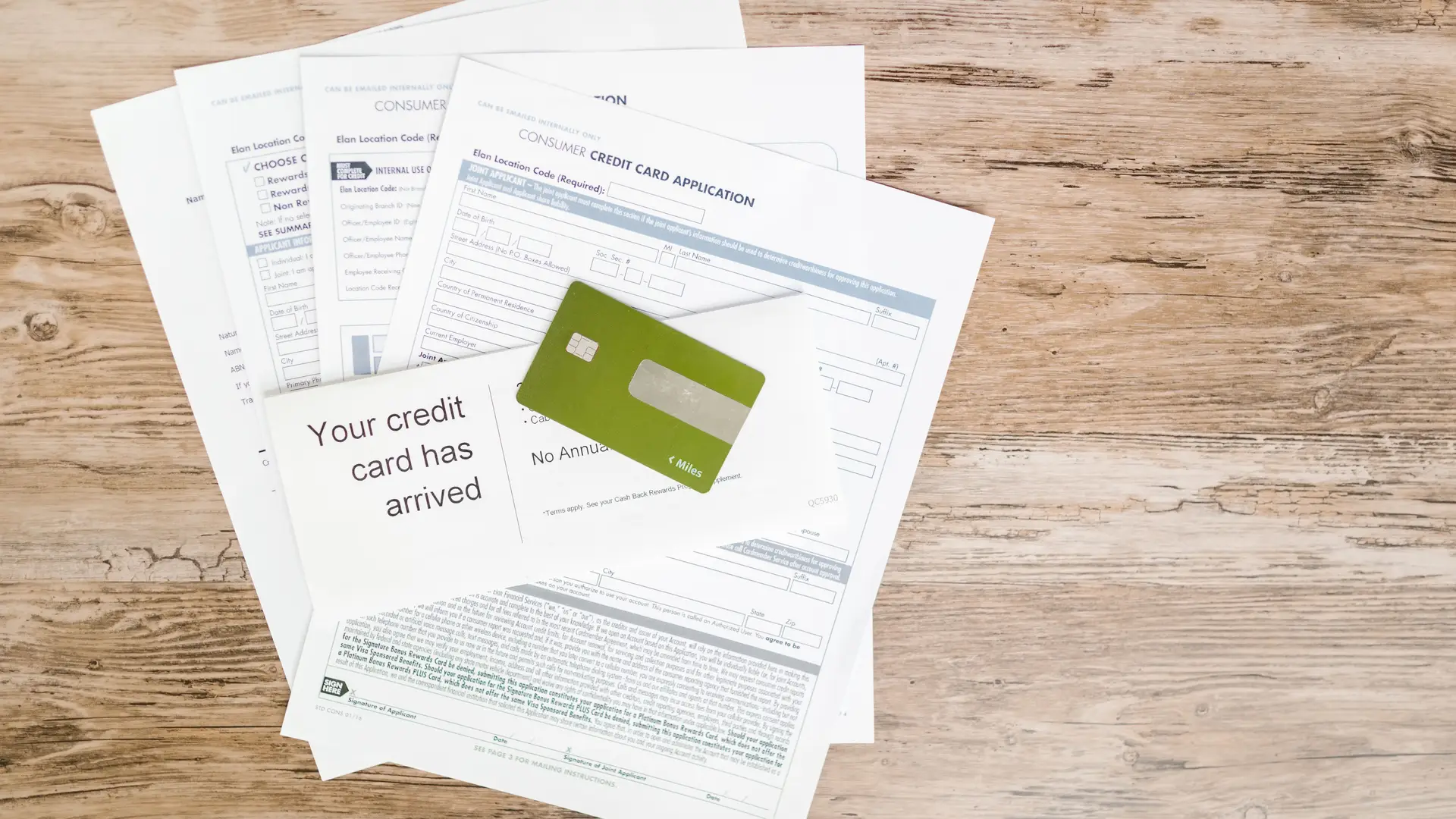 A credit card resting on printed documents on a wooden desk
