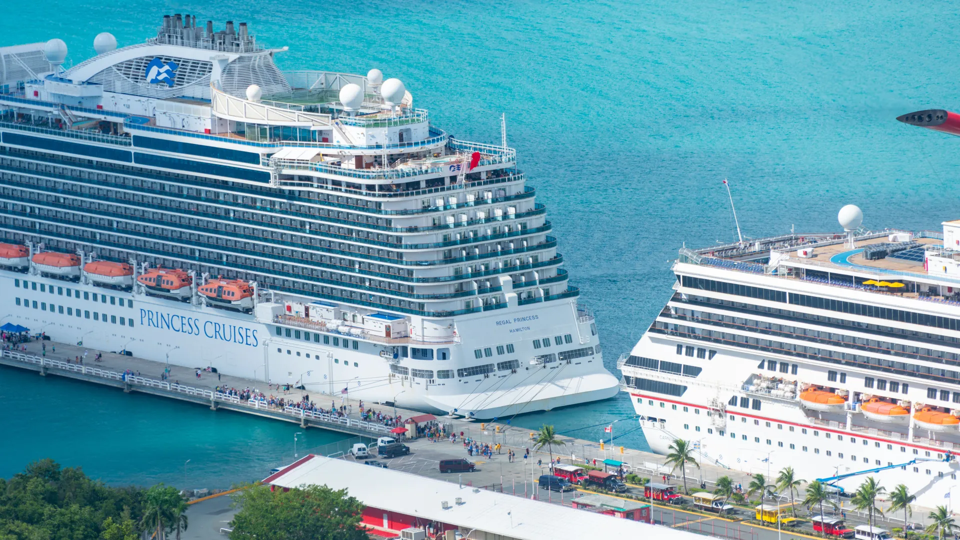Aerial view of large cruise ships docked at a pier in turquoise water