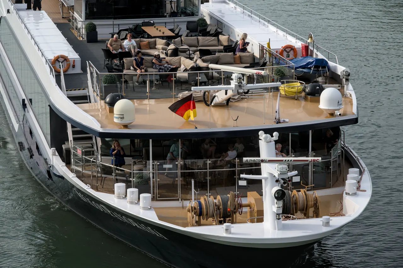 Elegant cruise ship loaded with passengers enjoying scenic views from the top deck.