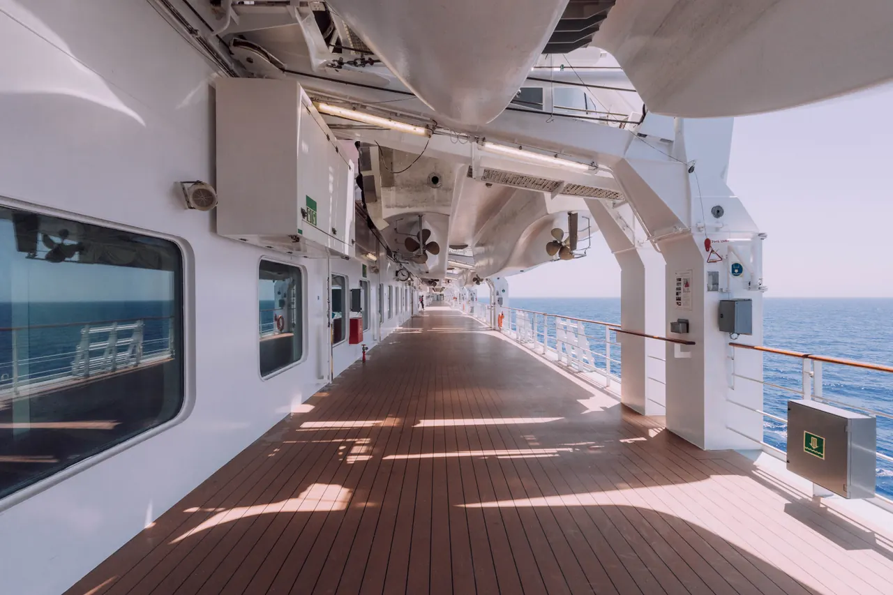 Spacious cruise ship deck overlooking the serene ocean under a clear sky.