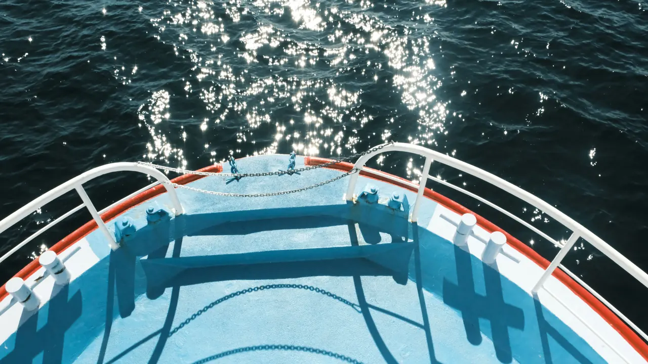 View from a boat’s bow with sunlight sparkling on the ocean water.