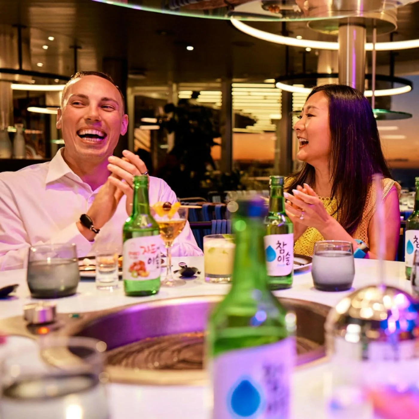 Sailors laughing over soju and Korean BBQ at Gunbae, Virgin Voyages' communal-table restaurant