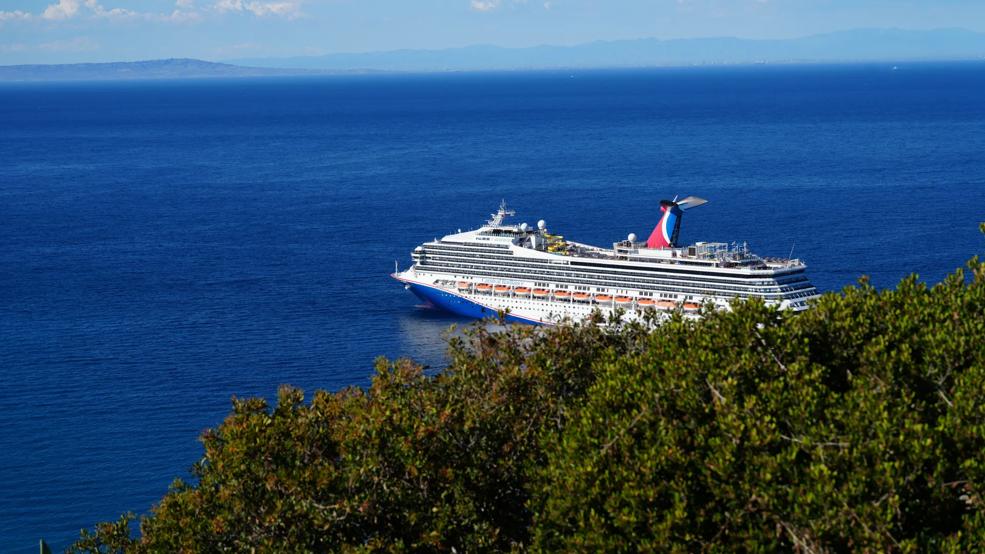 A large cruise ship under way across deep blue open water on a clear day