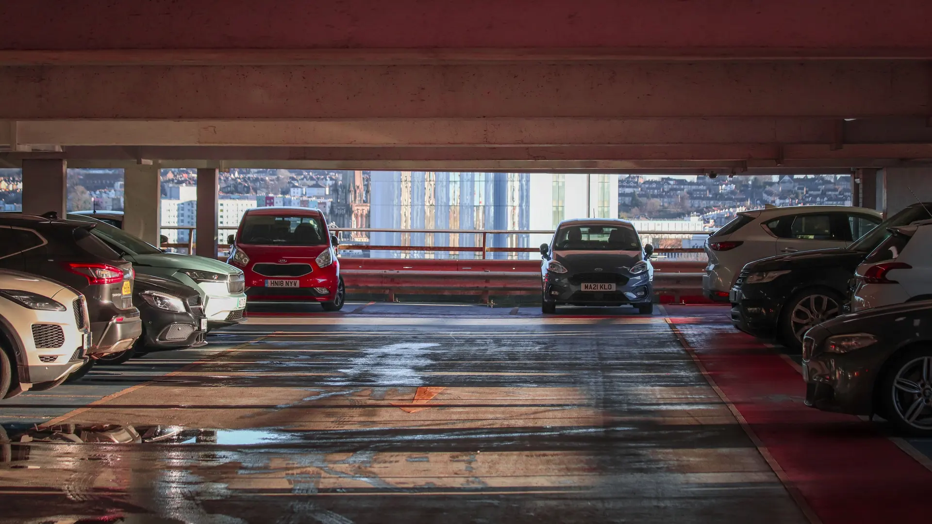 Cars parked on an upper level of a multi-storey car park overlooking a city