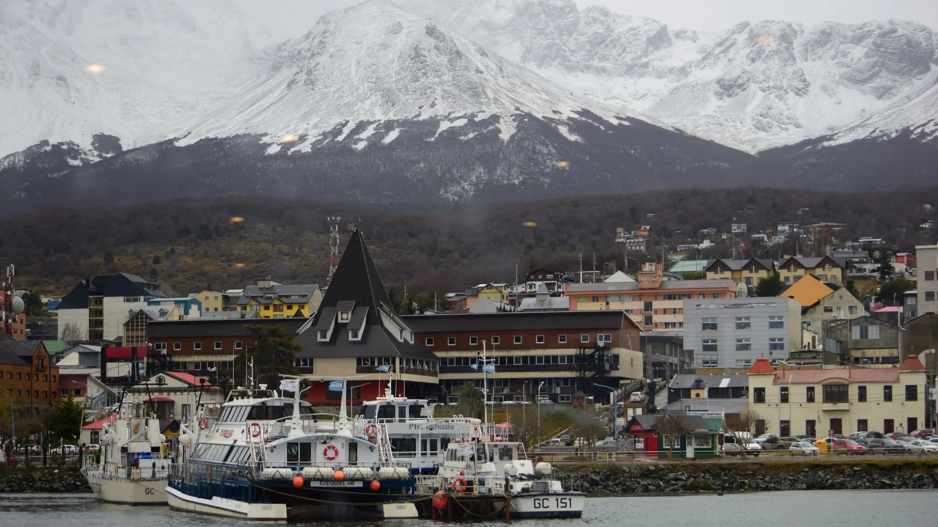 Boats in Ushuaia harbor with snow-capped mountains rising behind the town