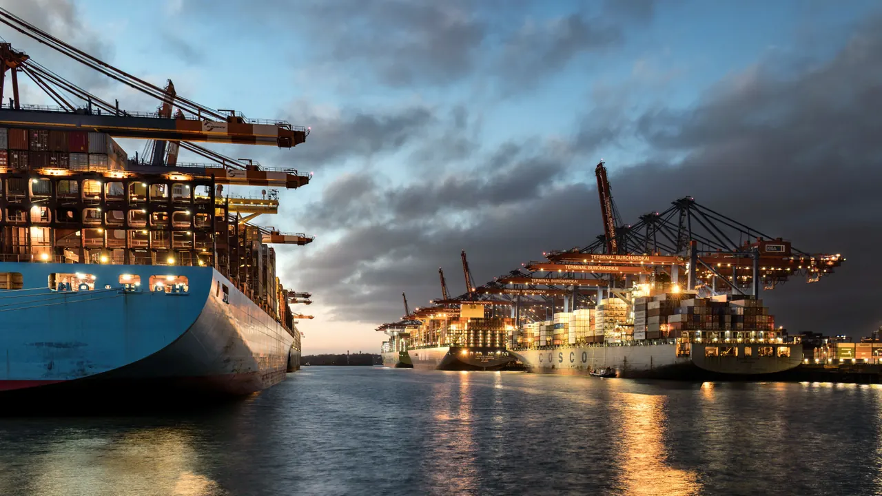 A breathtaking view of illuminated container ships and cranes in Hamburg harbor during dusk.