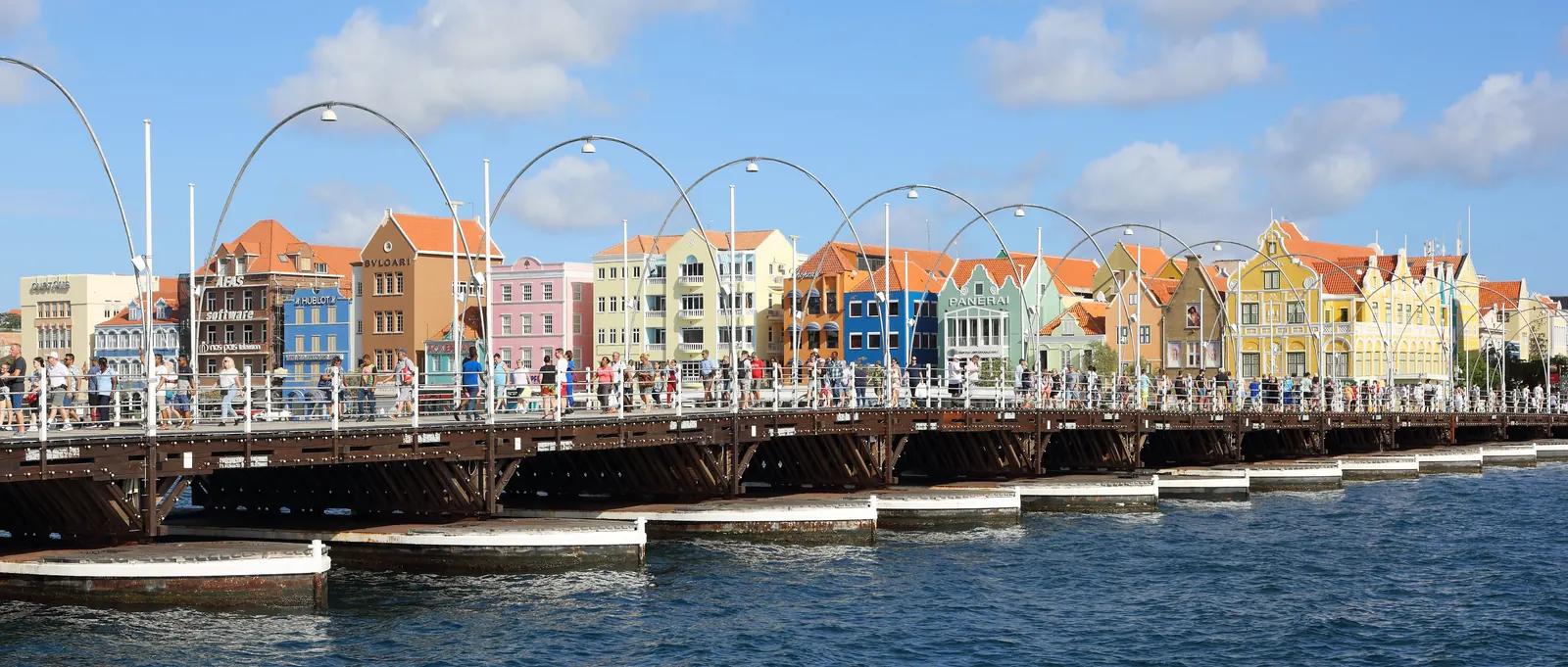 The colorful Dutch colonial facades of the Handelskade waterfront in Willemstad, with the Queen Emma pontoon bridge across St. Anna Bay