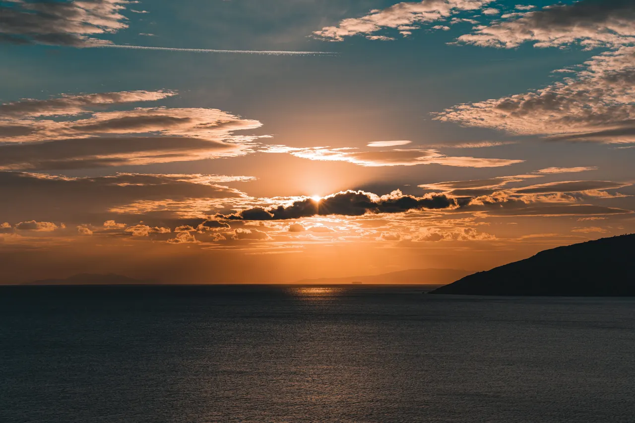 Breathtaking sunset over the ocean with dramatic clouds and golden hues.
